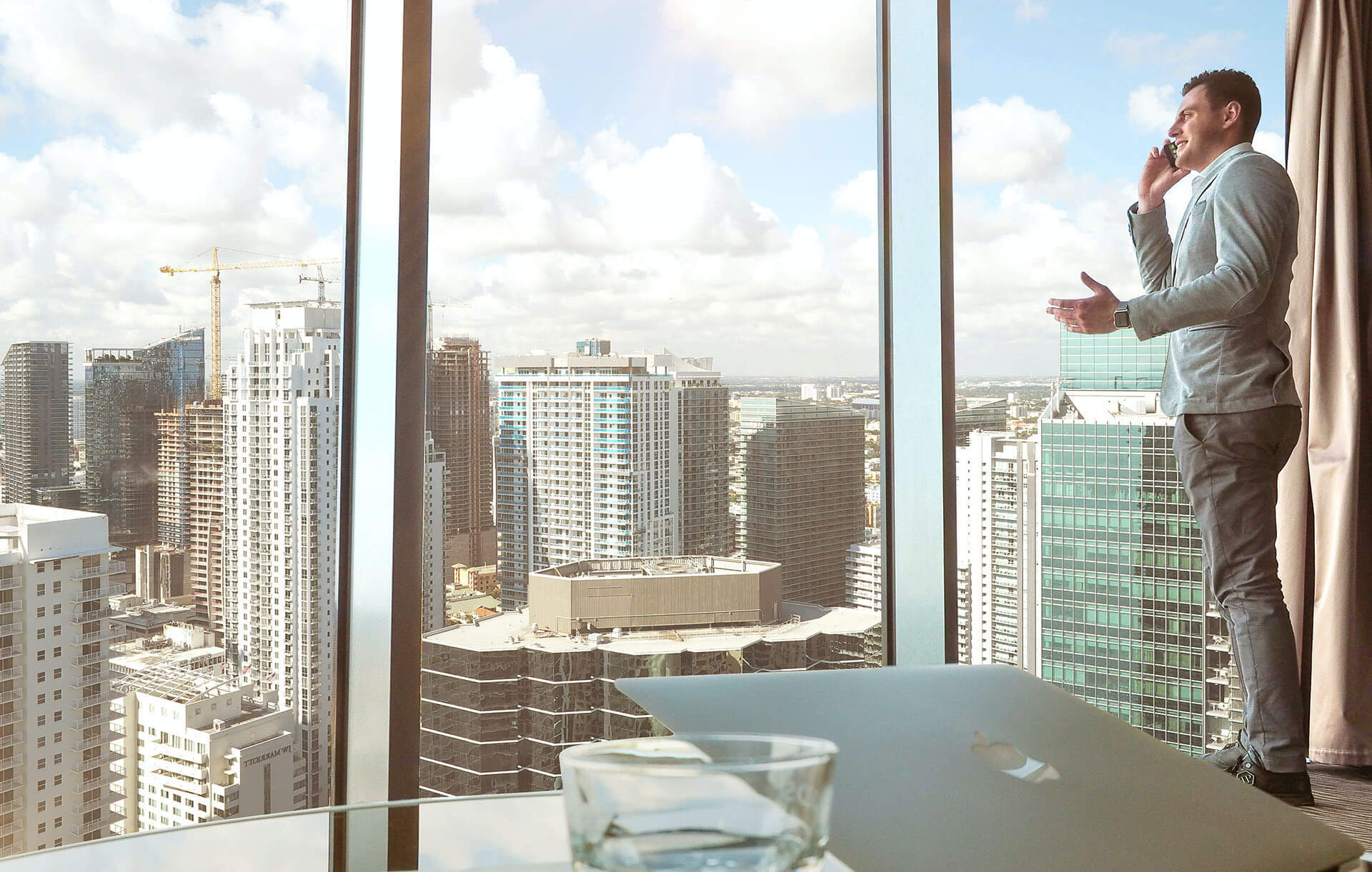 Imágen de persona hablando por celular mirando por una ventana en un piso alto