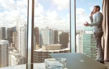 Imágen de persona hablando por celular mirando por una ventana en un piso alto